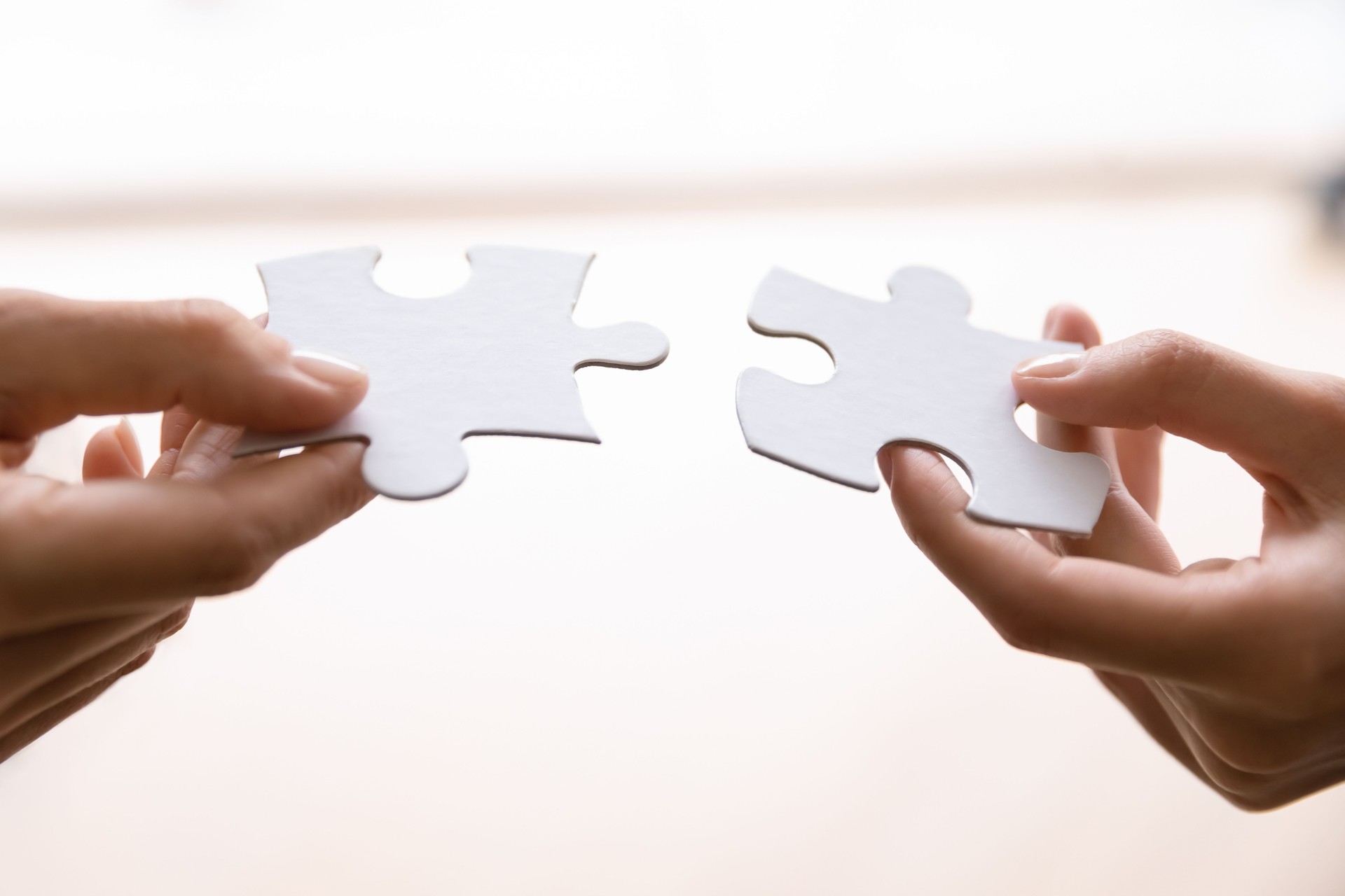 Human connecting two pieces of puzzle. Woman joining jigsaw parts