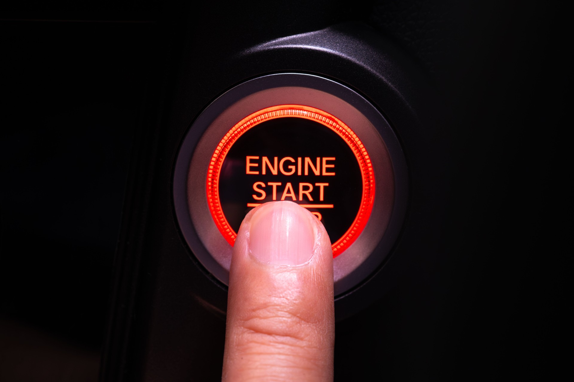 The driver's hand is pressing the car start button. Concept of transportation and technology